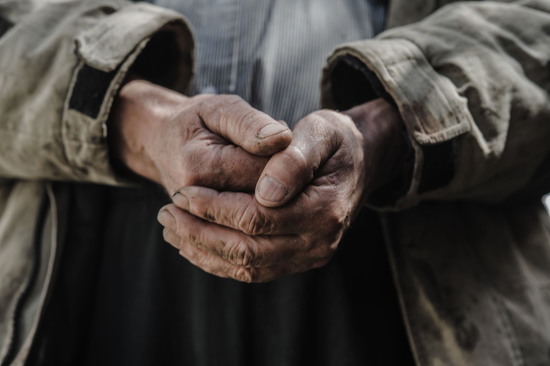 The homeless man's hands are caked with dirt and grime, rough from the cold